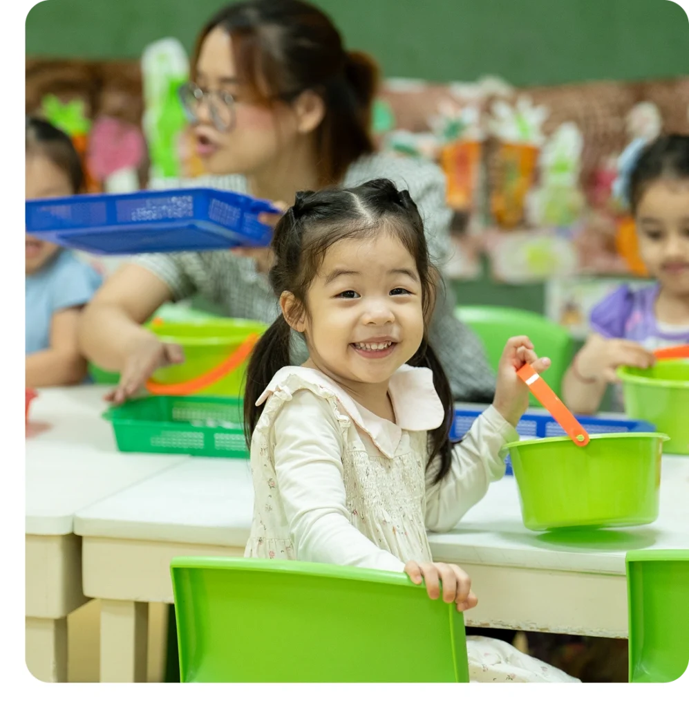 A young girl smiling warmly at the camera during a fun hands-on activity at Creative Play Corner